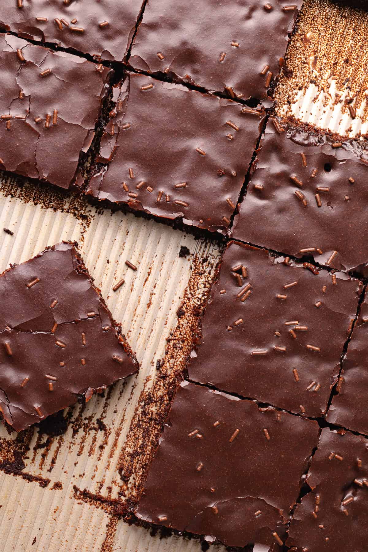 Dark chocolate sheet cake, also known as Texas sheet cake, is topped with a dark chocolate icing and chocolate sprinkles, and cut into squares.