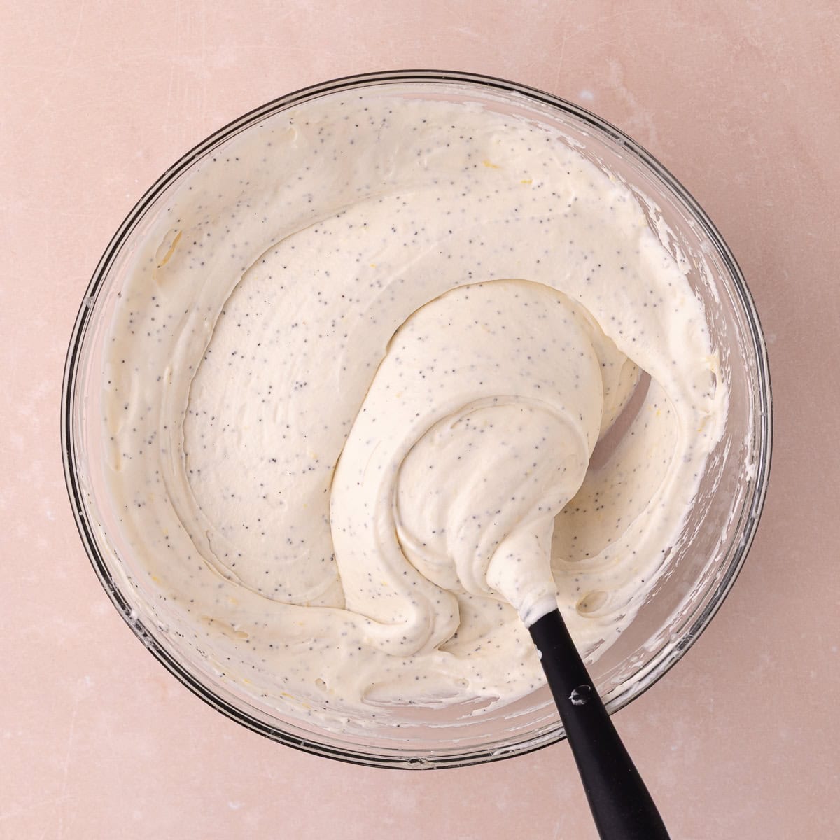 No-churn Lemon poppy seed ice cream is mixed together in a large glass bowl.