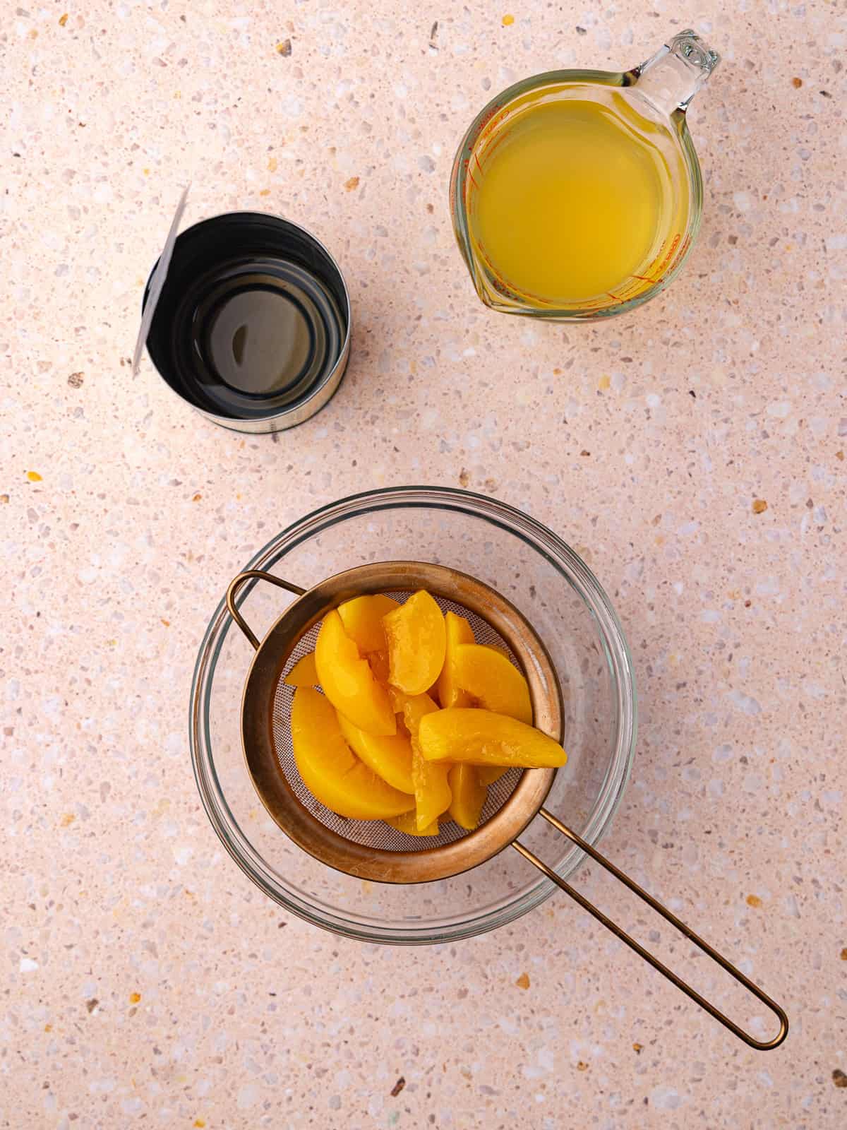 Canned peaches are drained to separate the sliced peaches from the syrup in the can.