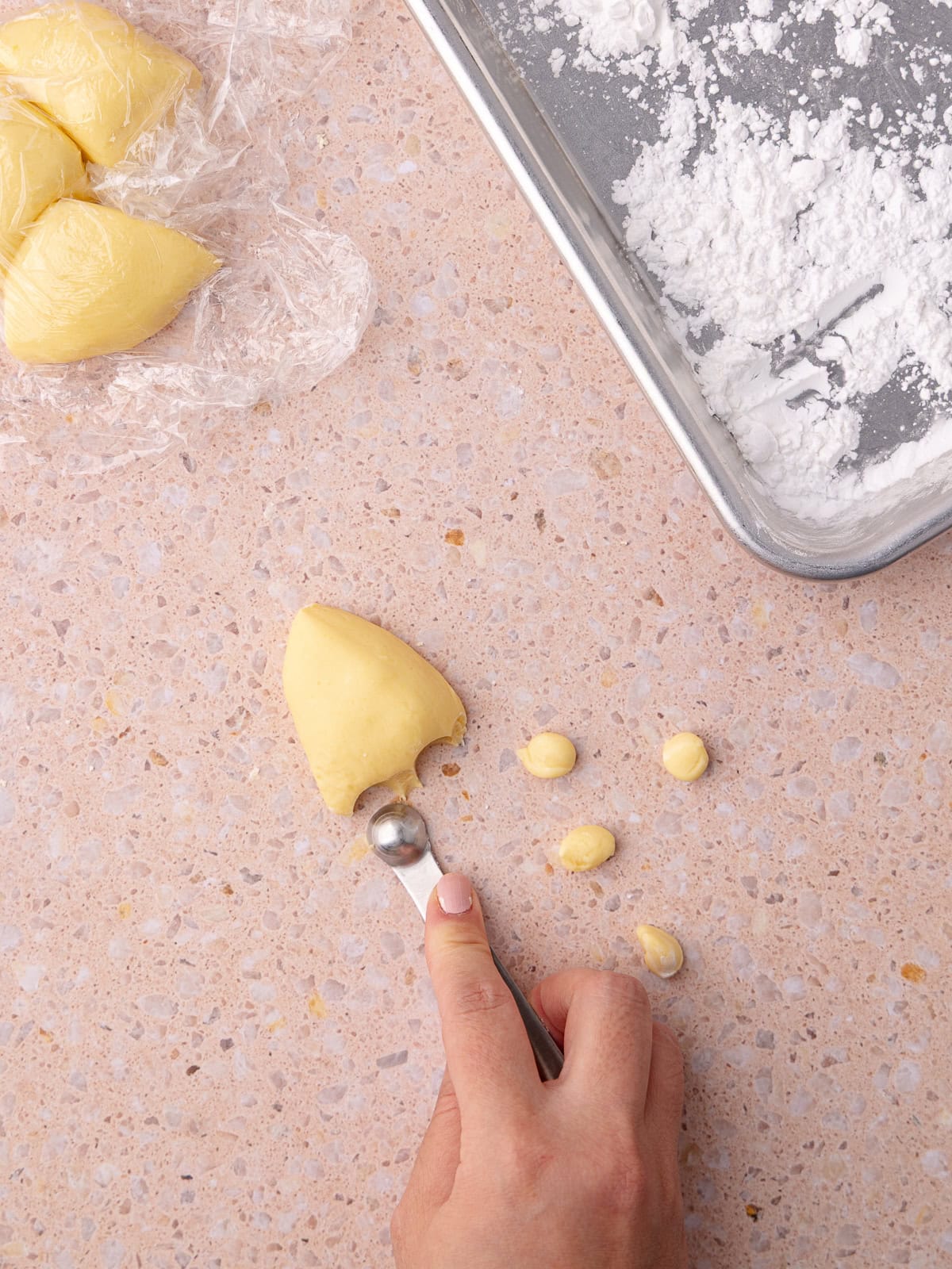 Homemade peach boba pearls are scooped with a ⅛ teaspoon spoon and are rolled into small balls.