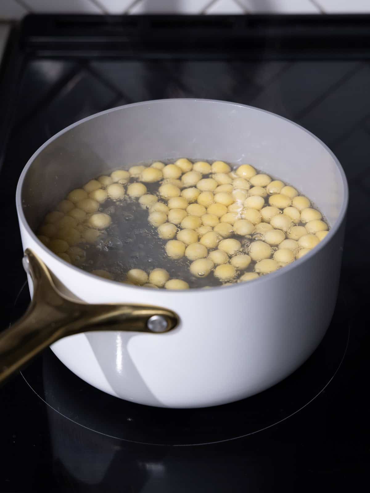 Homemade peach bubble pearls are cooked in a small saucepan in a low boil until tender.