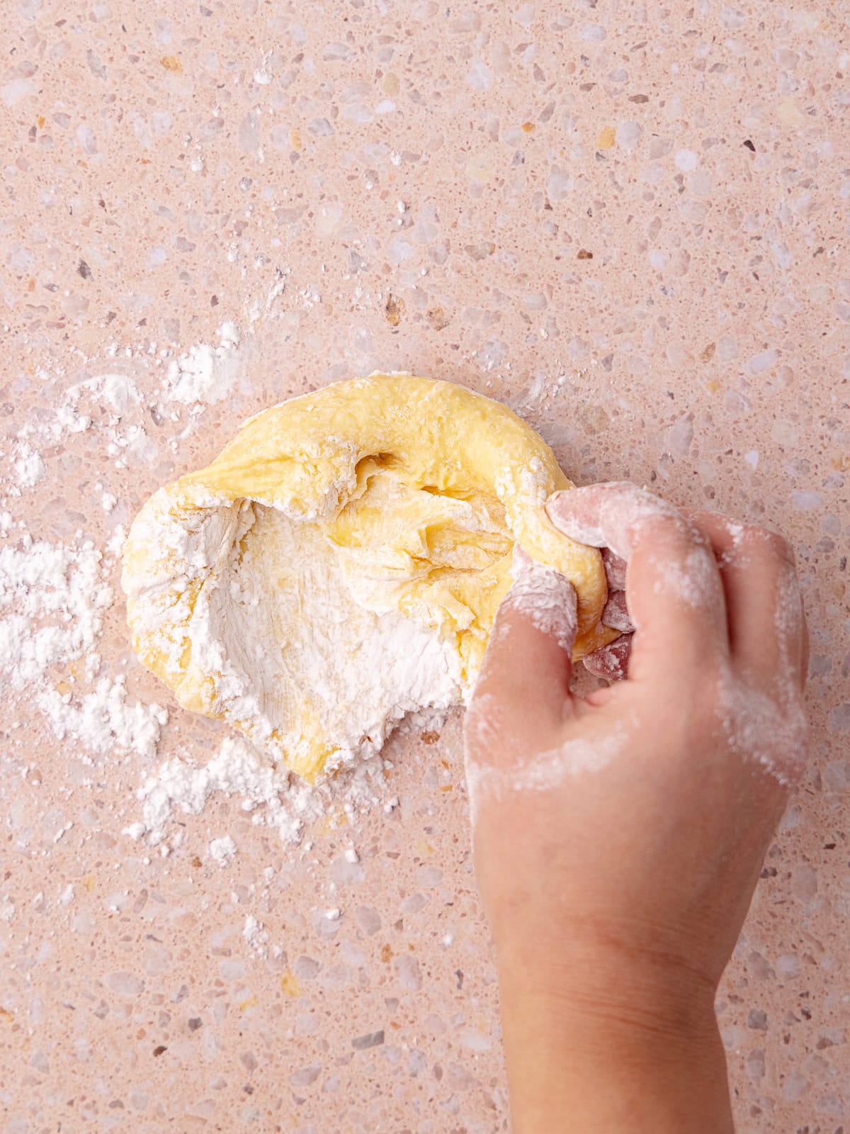 Peach flavored tapioca dough is kneaded until a smooth ball forms.
