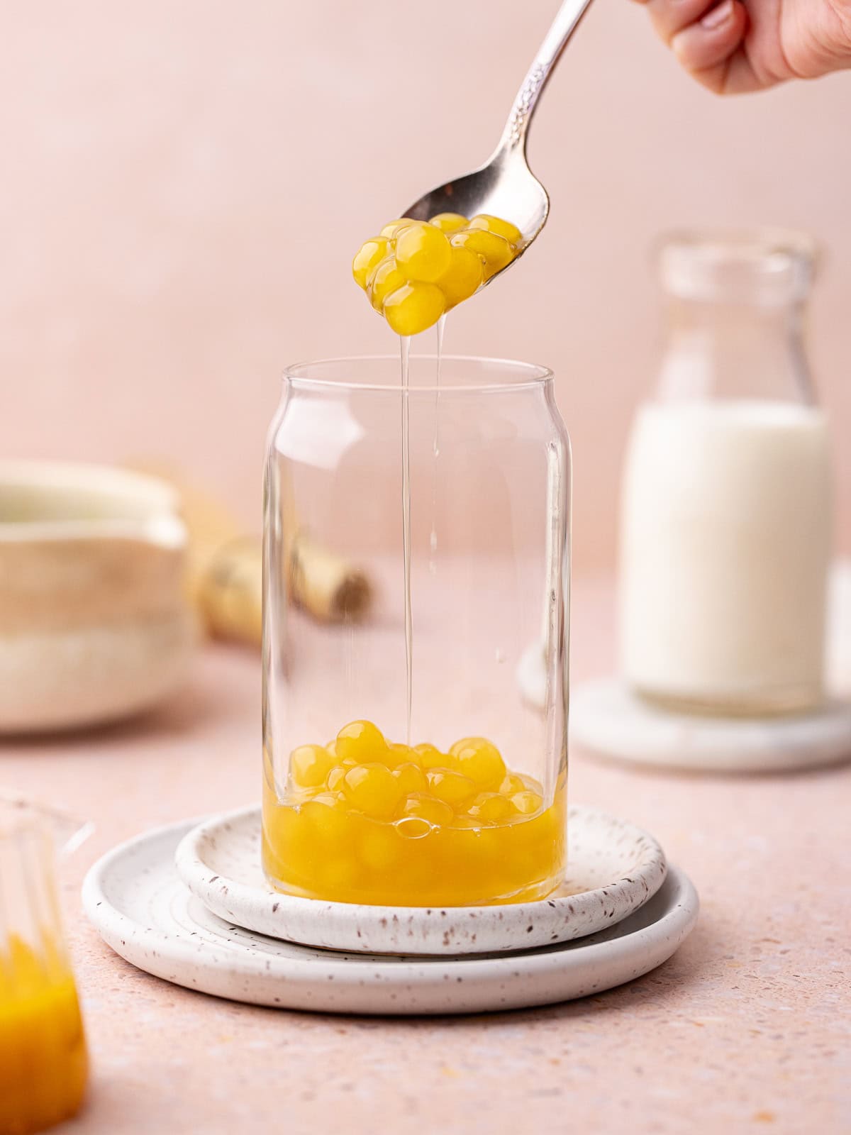 Cooked homemade peach boba pearls are added to a tall glass.