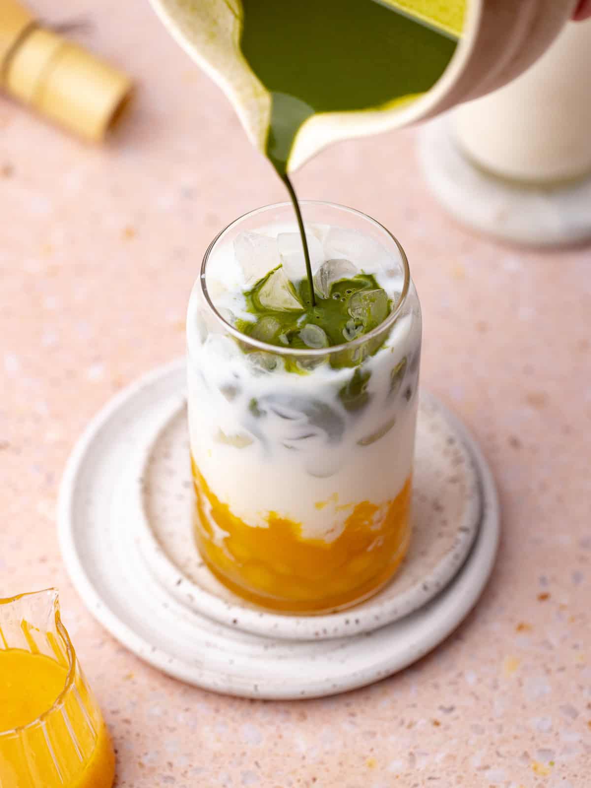 Matcha tea is added over the milk, ice, peach puree and homemade peach bubble pearls.