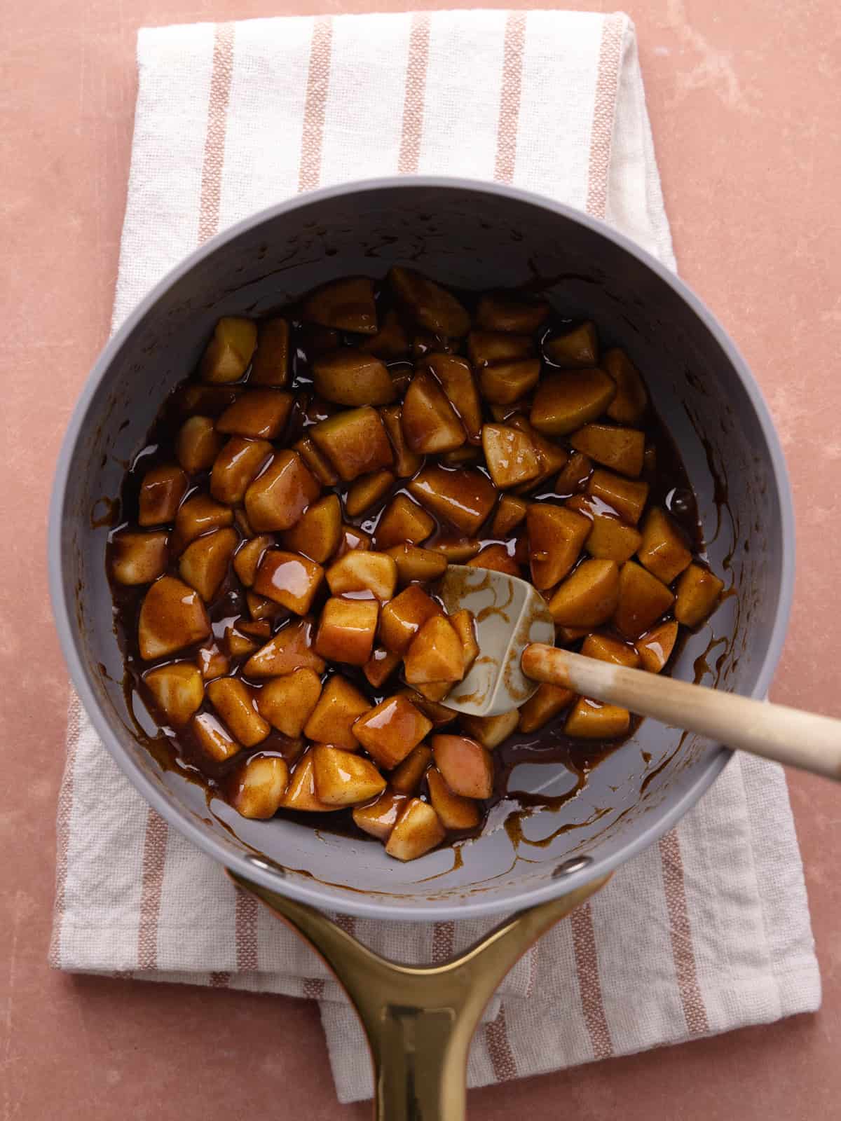 Apple fritter filling which include diced apples, butter, brown sugar, cinnamon, nutmeg, cornstarch and water, is cooked together in a small saucepan.