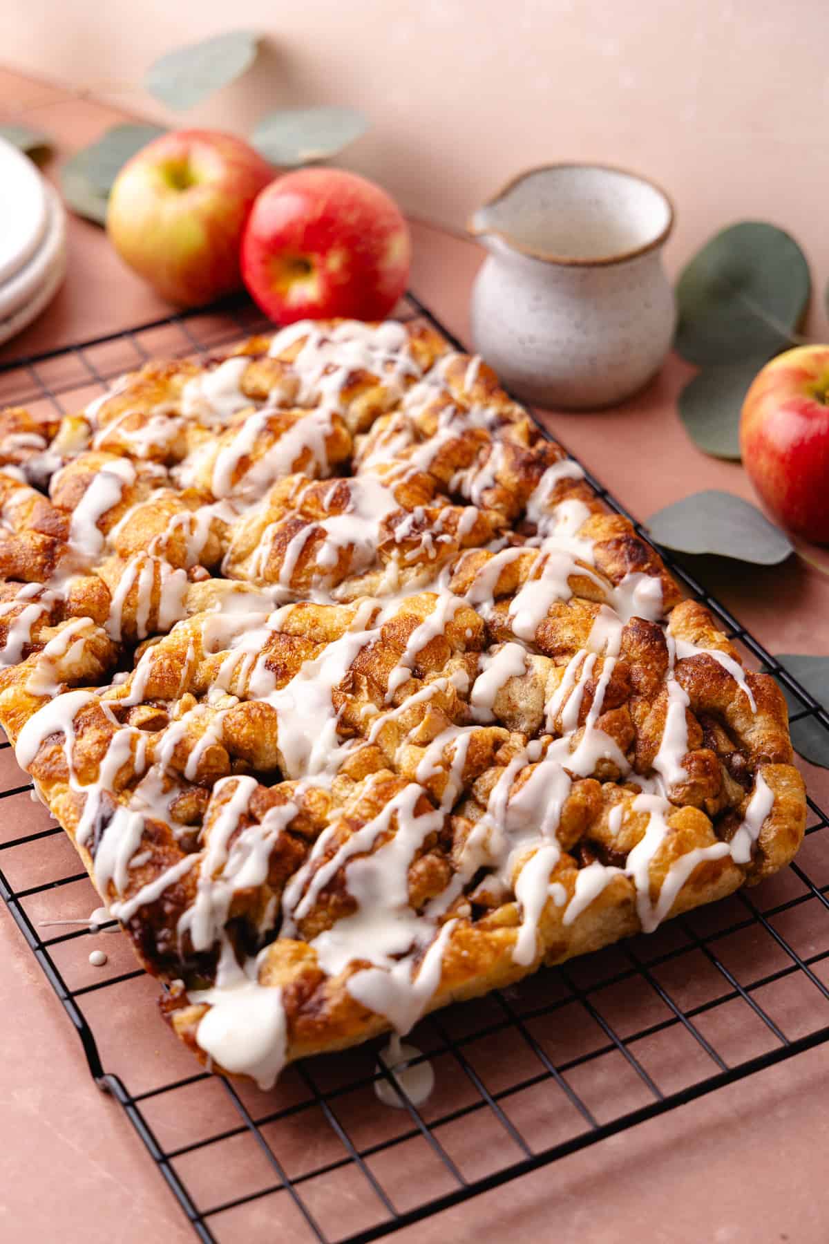 Soft and fluffy pull-apart apple fritter focaccia is topped with a delicious maple glaze and is sitting on a wire rack.