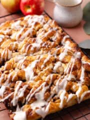 Soft and fluffy pull-apart apple fritter focaccia is topped with a delicious maple glaze and is sitting on a wire rack.