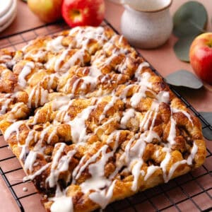 Soft and fluffy pull-apart apple fritter focaccia is topped with a delicious maple glaze and is sitting on a wire rack.