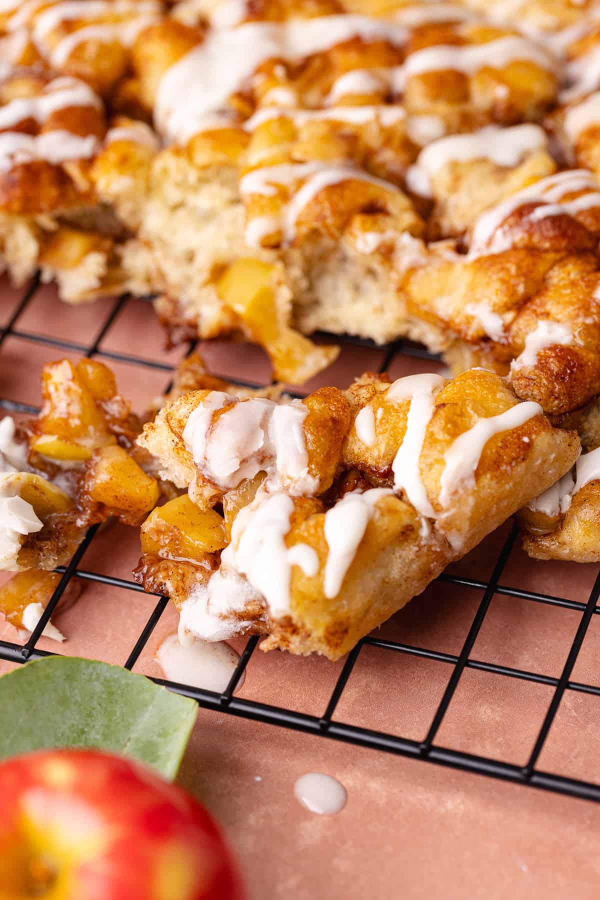 Soft and fluffy pull-apart apple fritter focaccia is topped with a delicious maple glaze and is sitting on a wire rack.