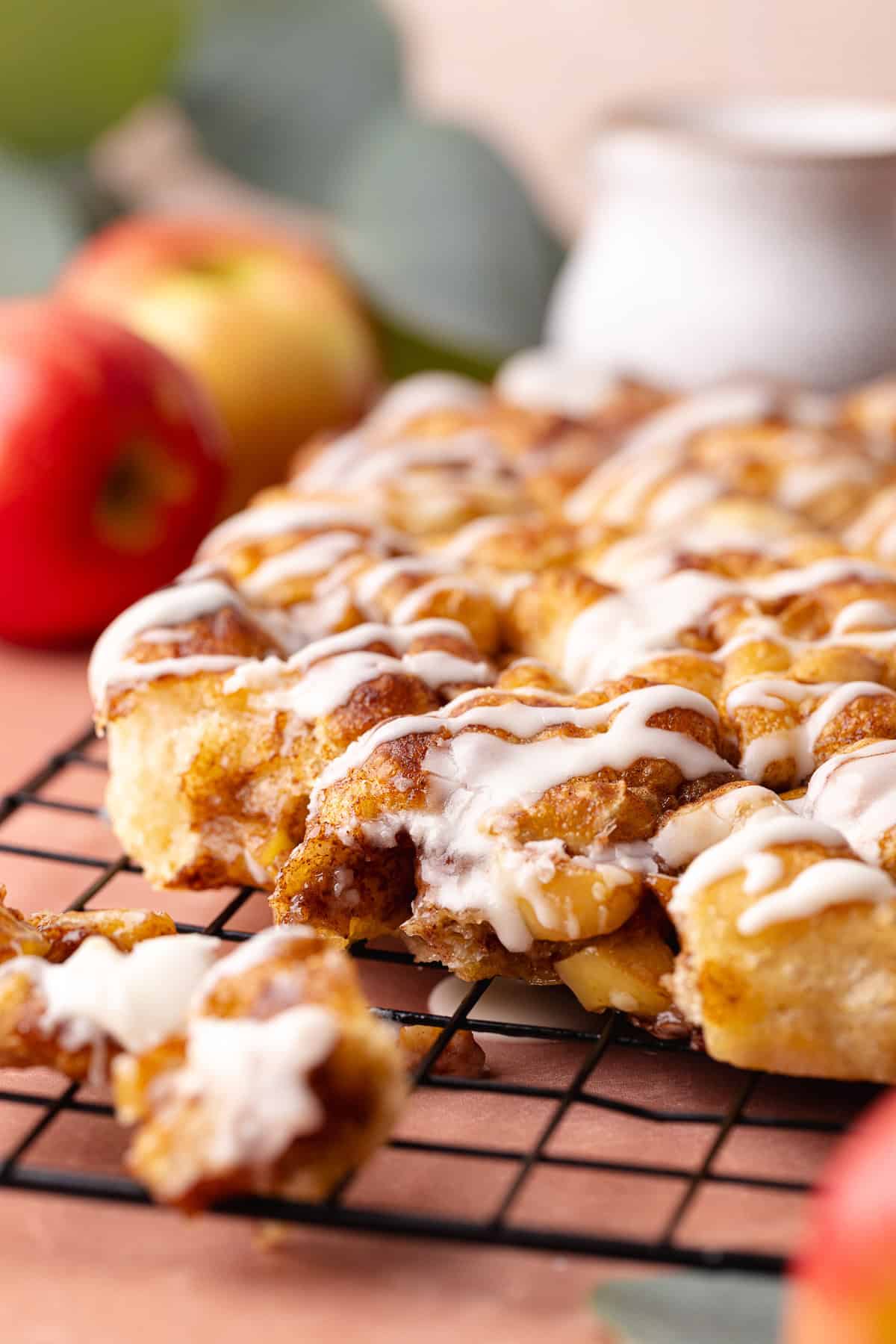 Soft and fluffy pull-apart apple fritter focaccia is topped with a delicious maple glaze and is sitting on a wire rack.