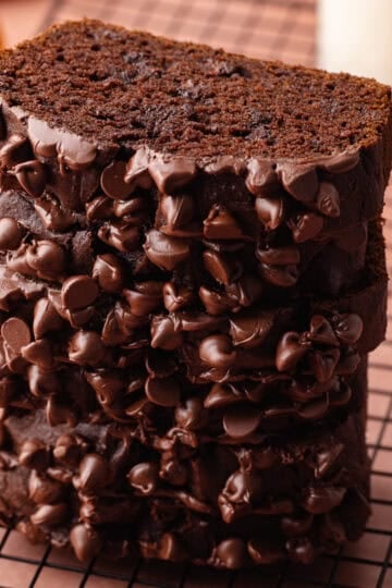 Super moist chocolate pumpkin bread studded with chocolate chips is sliced and stacked on a wire rack.