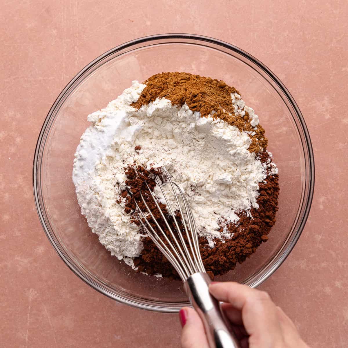 All-purpose flour, cocoa powder, pumpkin pie spice, cinnamon, baking soda and salt are whisked together in a small mixing bowl.