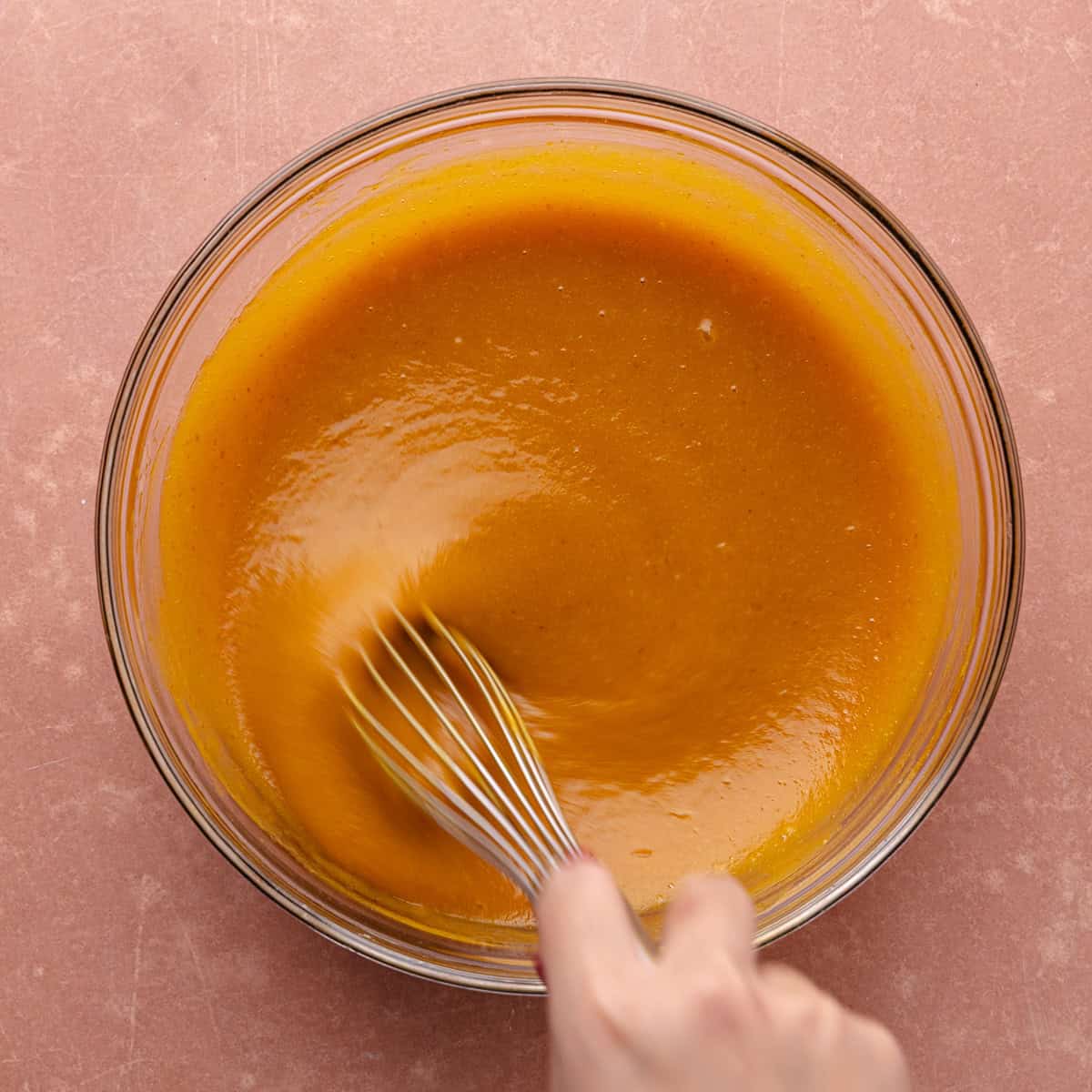 Oil, pumpkin puree, white sugar, brown sugar, vanilla extract and eggs are whisked together in a glass mixing bowl until well combined.