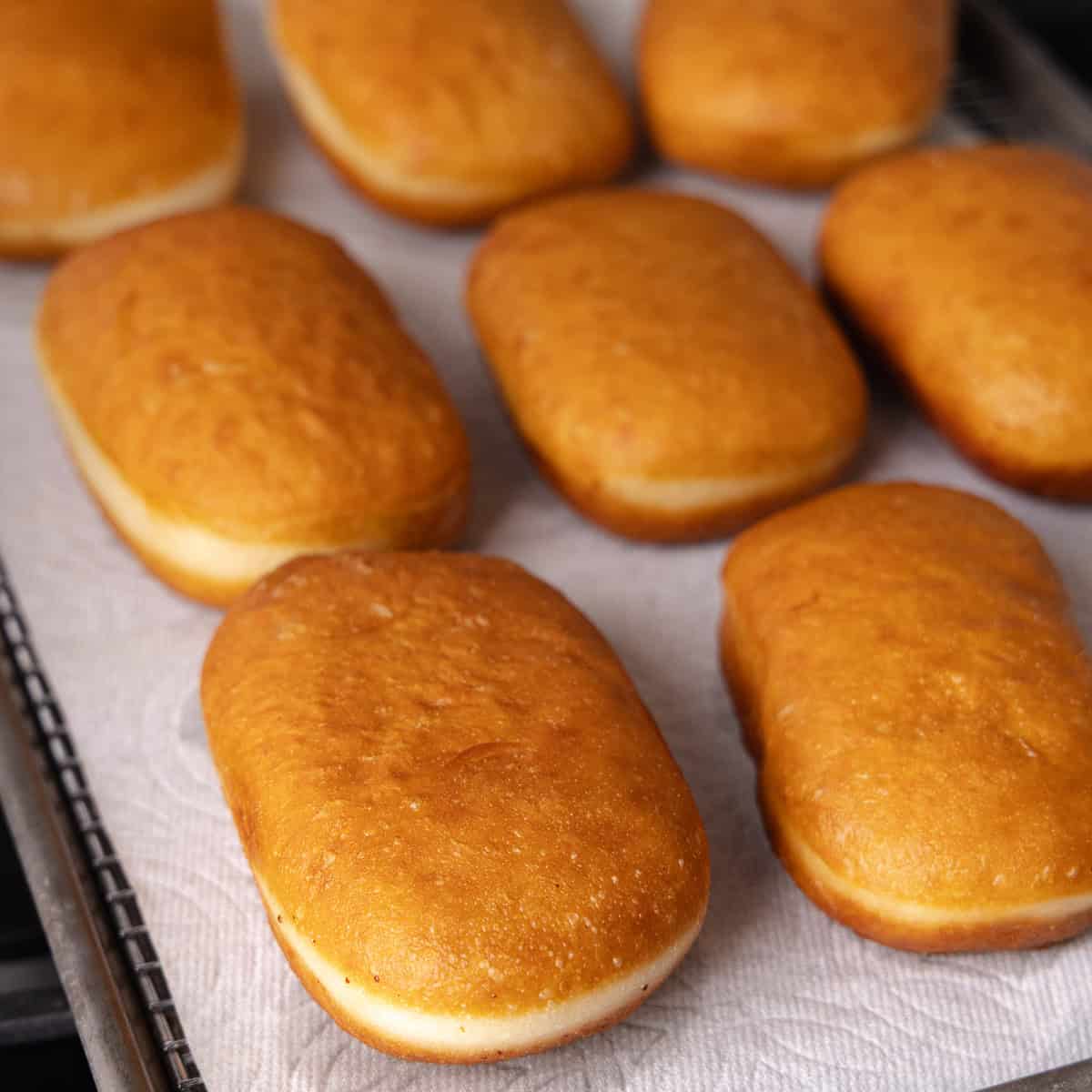 Maple donut bars are fried until golden brown and sitting on a wire rack lined with paper towels.