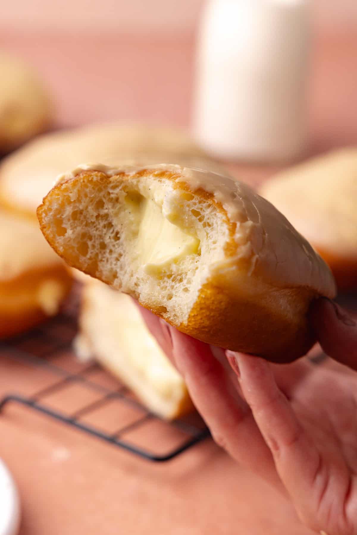 Maple bar donuts are filled with vanilla pastry cream and glazed in maple icing and sitting on a wire rack.