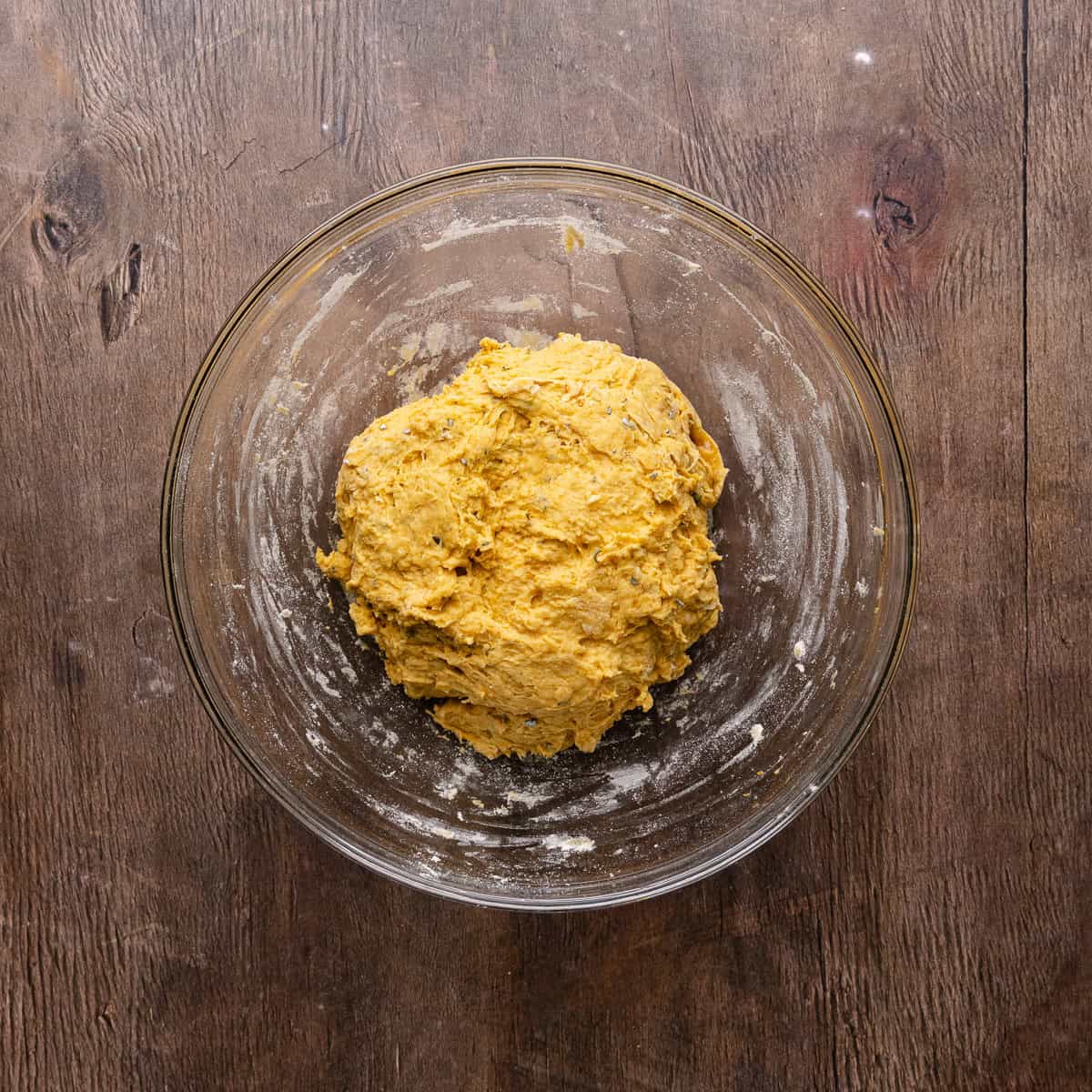 Soft pumpkin sage pretzels dough is kneaded together into a mixing bowl.