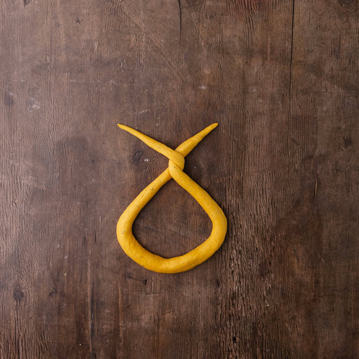 The ends of pumpkin sage pretzel dough are twisted together twice.