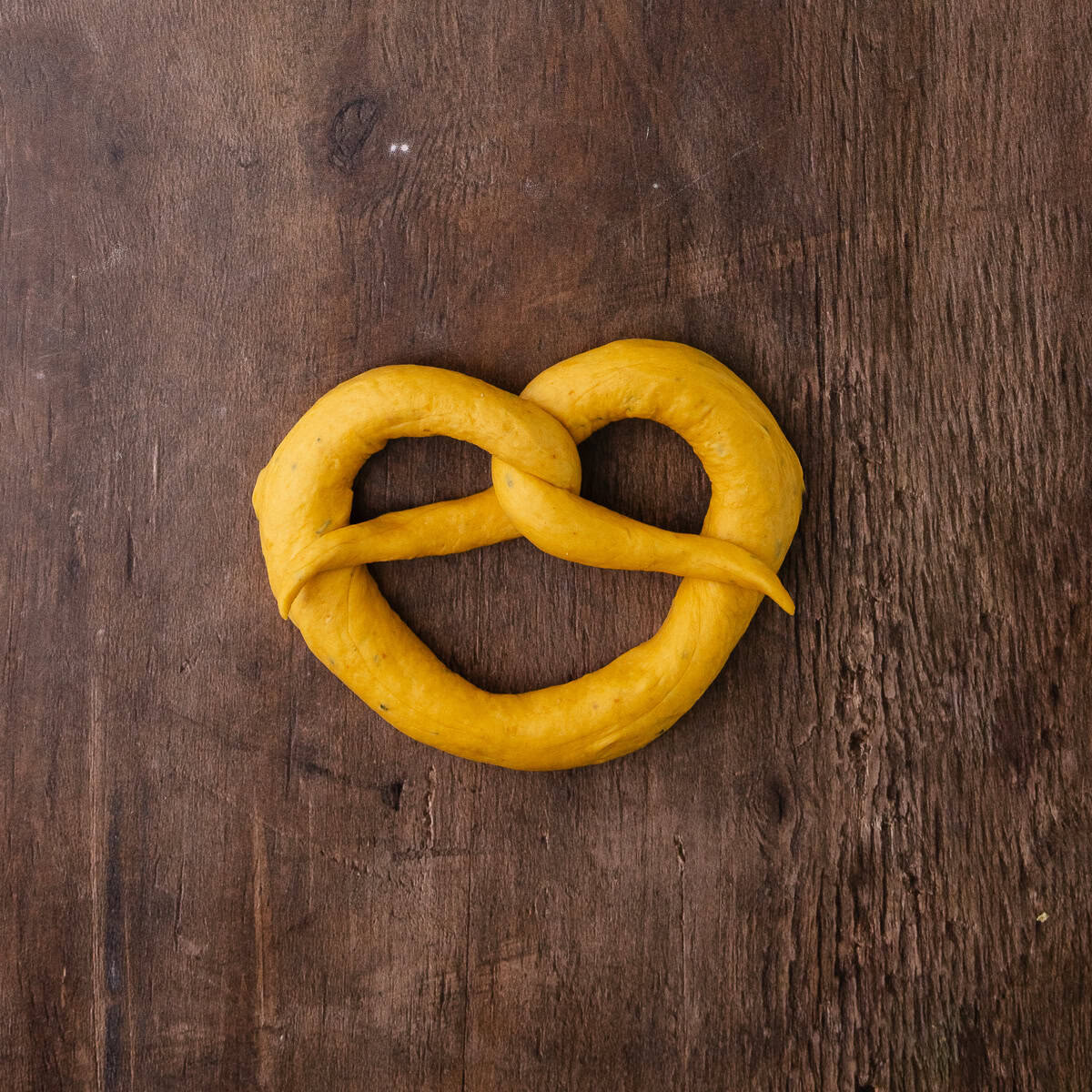 The pumpkin sage pretzel dough is shaped into a pretzel.