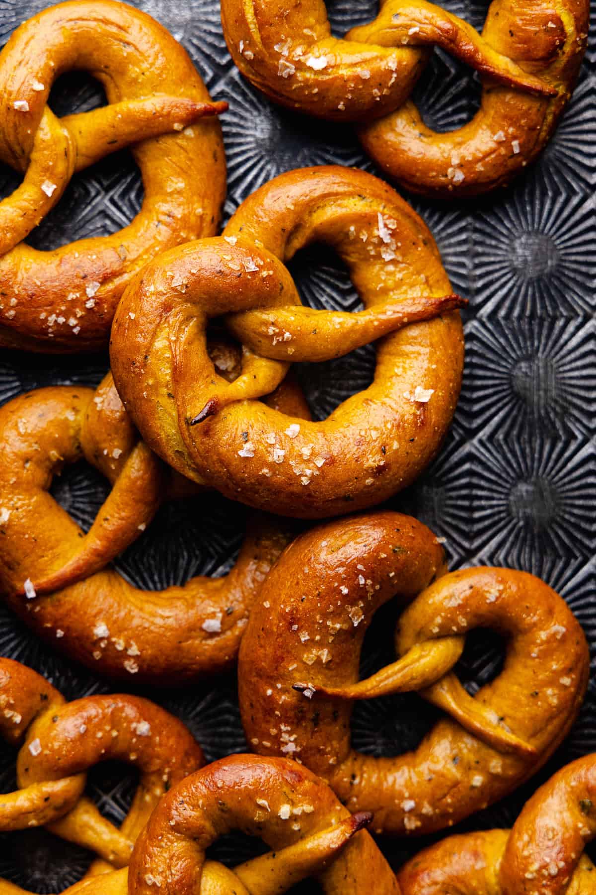 Soft pumpkin sage pretzels are topped with flaky sea salt and baked until golden brown and shiny.