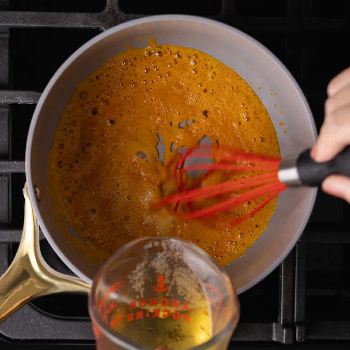 Beer is slowly drizzled into the saucepan with a roux.