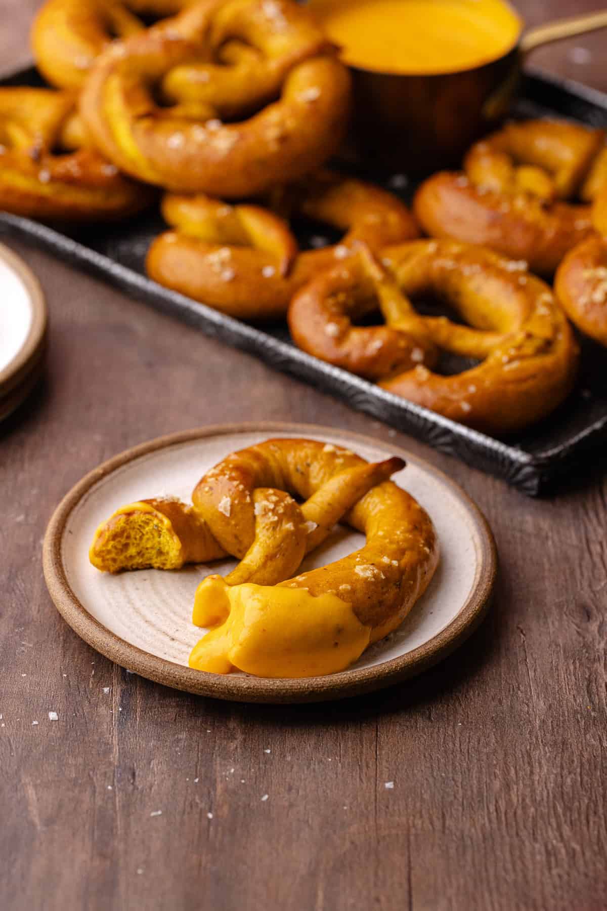 Soft pumpkin sage pretzels are topped with flaky sea salt and baked until golden brown and shiny and dipped in a spicy cheese beer sauce.