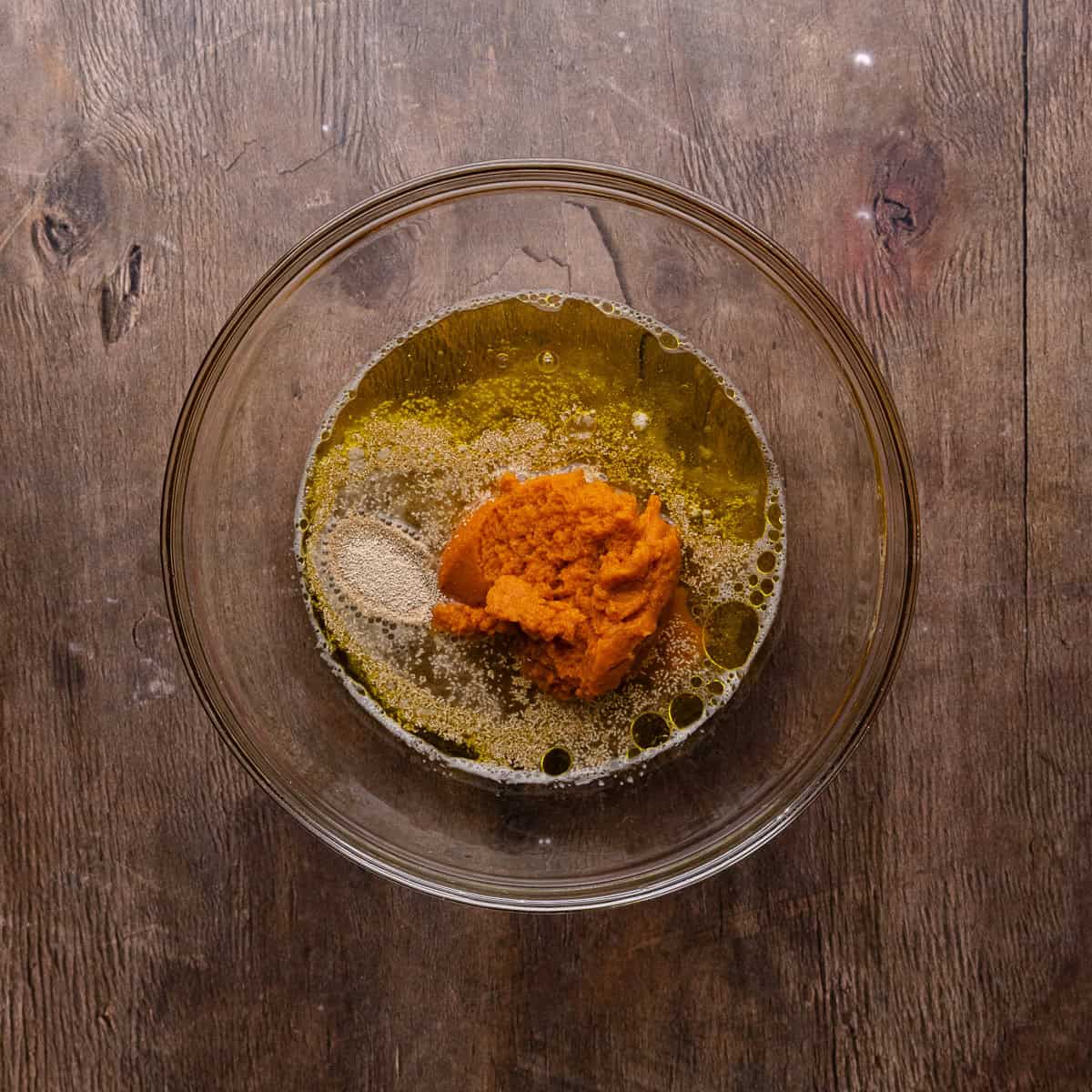 Beer, yeast, honey, olive oil and pumpkin puree are in a mixing bowl.