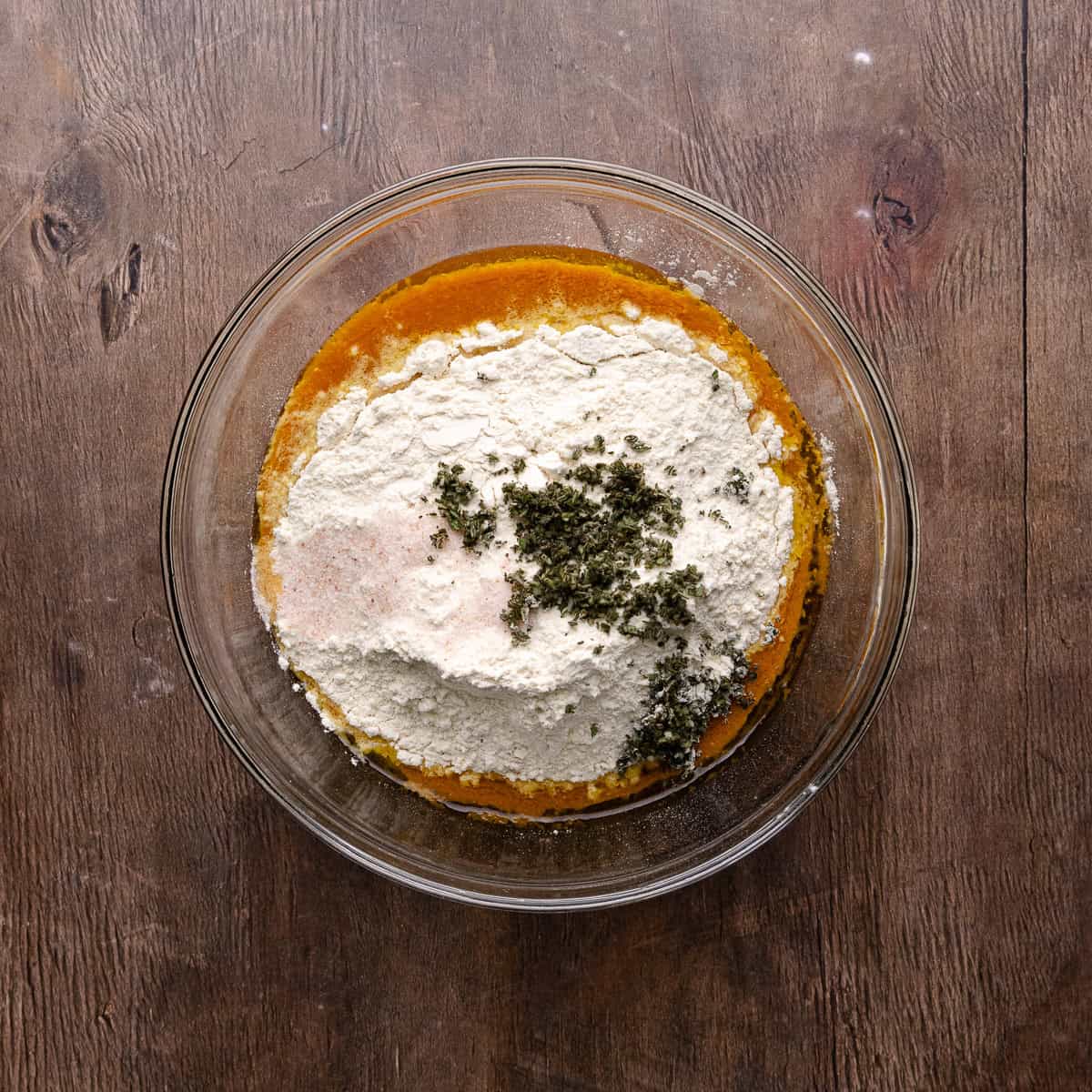 Bread flour, salt and finely chopped sage leaves are added to the wet ingredients.