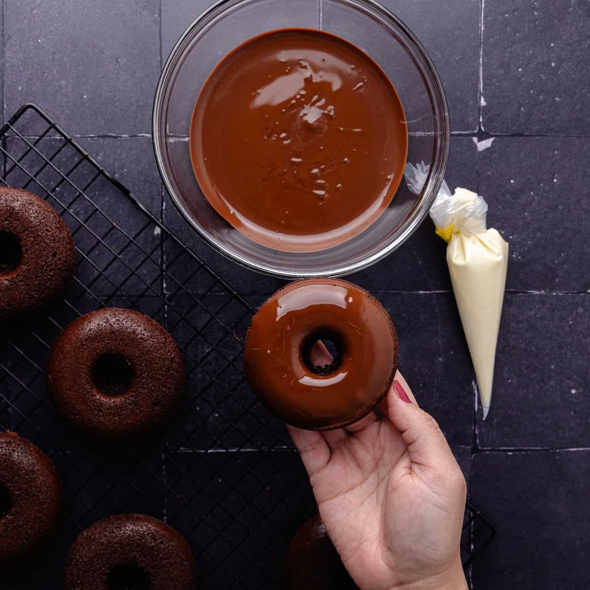 Baked chocolate chip donuts are dipped into melted chocolate.