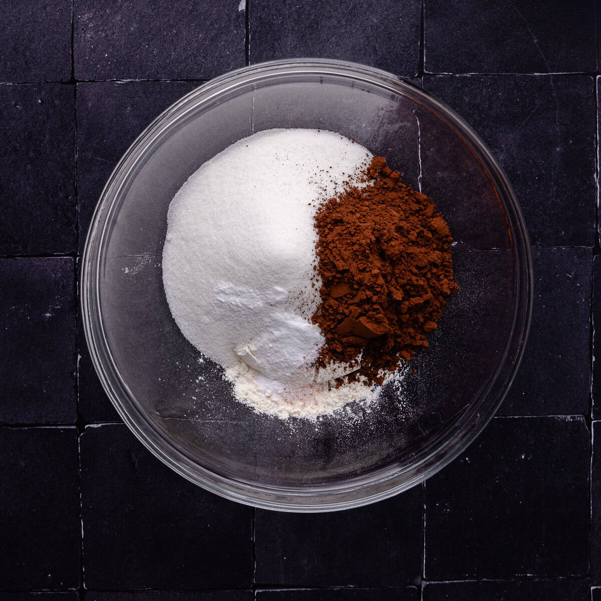 Flour, sugar, cocoa powder, salt and baking soda are in a medium mixing bowl.