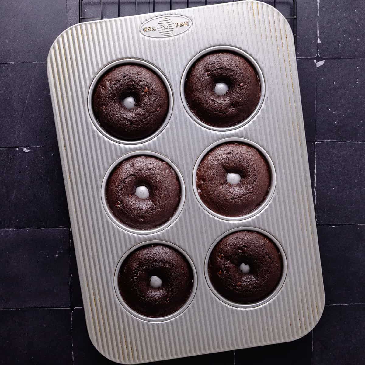 Donut batter with mini chocolate chips are baked in a donut pan.